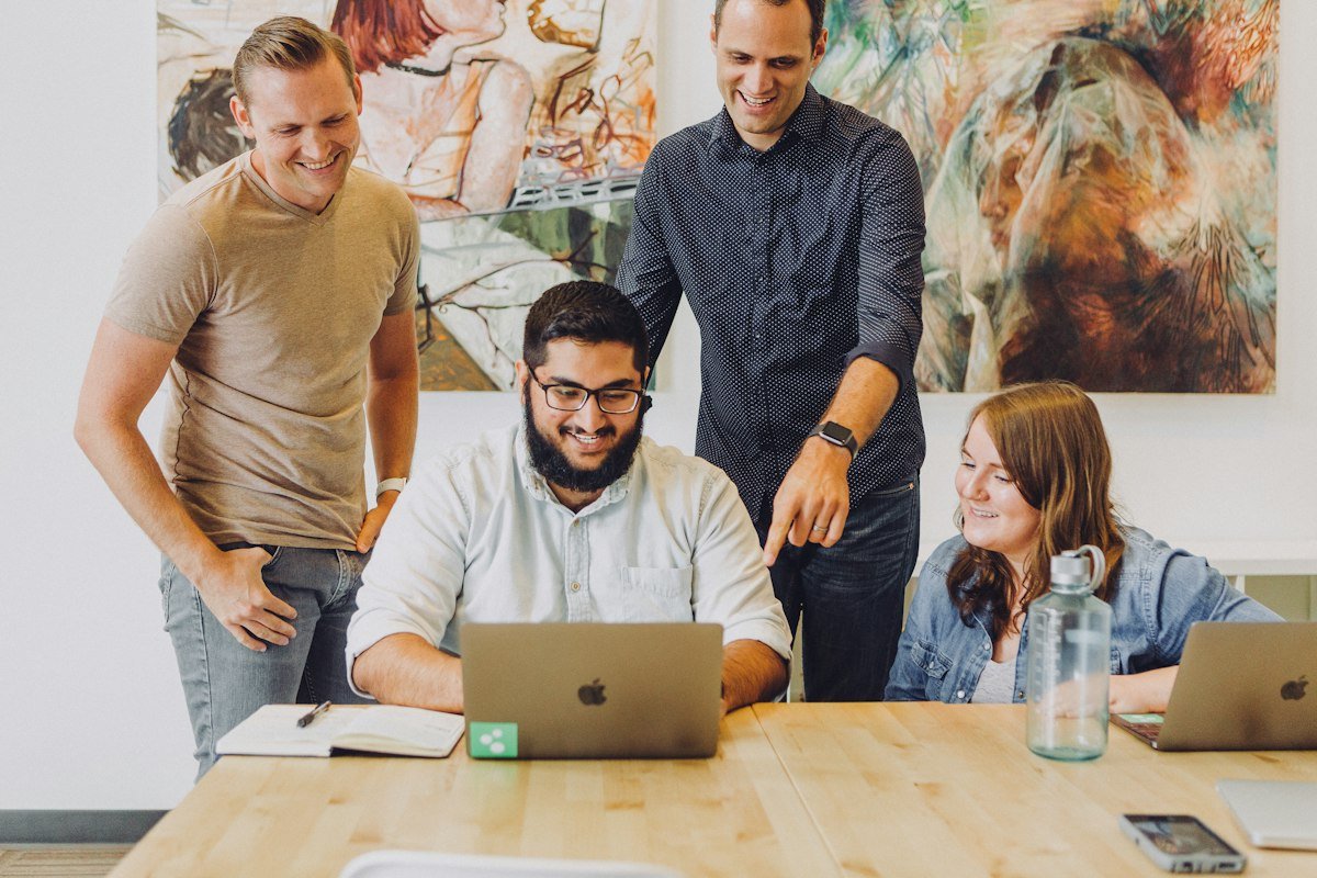 A team gathered around a laptop, smiling